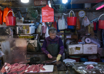 A fishmonger works at her stall at the Wan Chai wet market in Hong Kong on January 5, 2019. (Photo by ISAAC LAWRENCE / AFP)