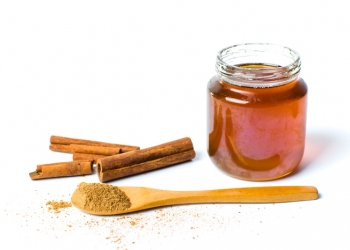 Jar of honey and cinnamon isolated on white