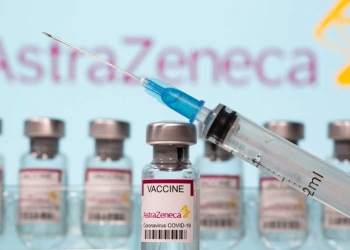 Vials labelled "AstraZeneca COVID-19 Coronavirus Vaccine" and a syringe are seen in front of a displayed AstraZeneca logo in this illustration taken March 10, 2021. REUTERS/Dado Ruvic/Illustration