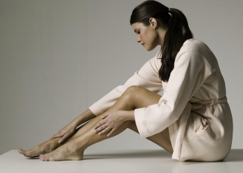 Young woman stroking legs, posing in studio, portrait