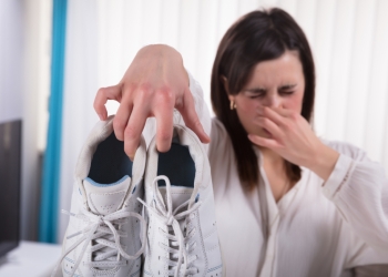 Woman Holding Dirty Stinky Shoes Covering Her Nose