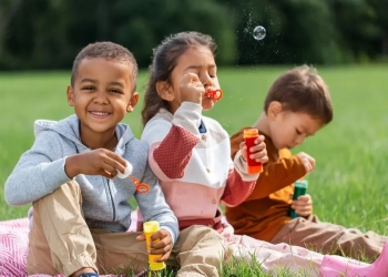 childhood, leisure and people concept - group of children blowing soap bubbles at park