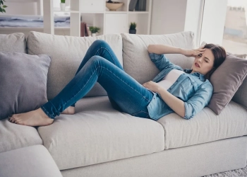 Full size photo of upset depressed girl have sick leave lying on sofa suffer from constipation, food poisoning pms wear denim jeans clothes indoors