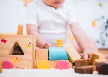 Asian child building playing toy blocks wood indoors room
