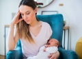 Stressed Mother Holding Crying Baby Suffering From Post Natal Depression At Home